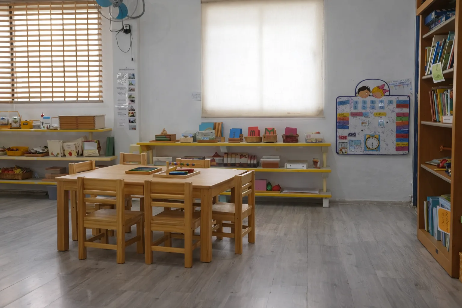 Salón Montessori con estanterías bajas y mesas de trabajo